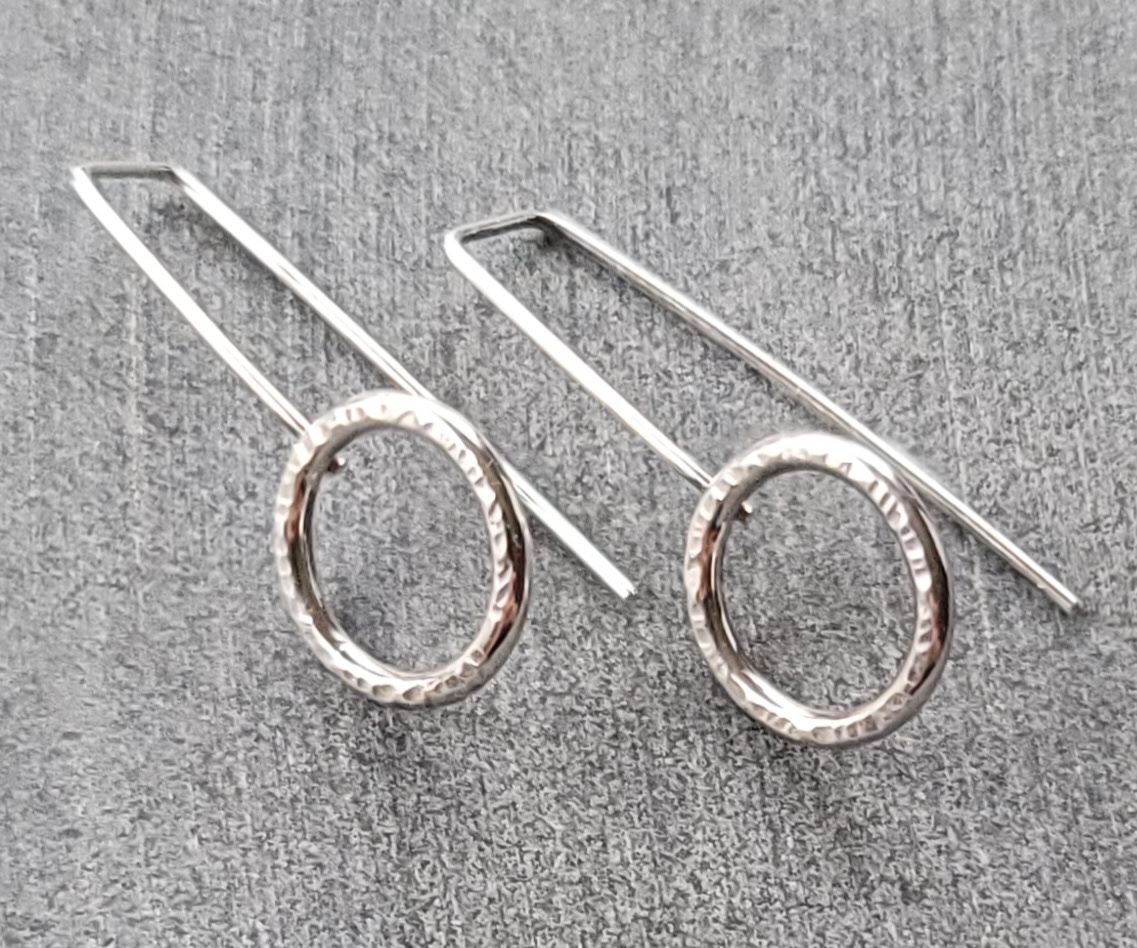 hand crafted silver earrings. a patterned ring on a long slender ear wire